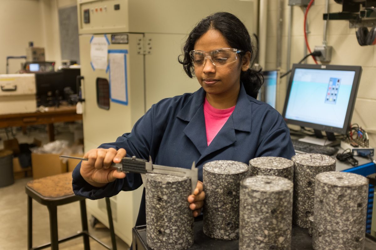 Haritha Malladi is measuring the dimensions of cored asphalt concrete specimens for a dynamic modulus test. She says she loves the hands-on aspect of her research. 